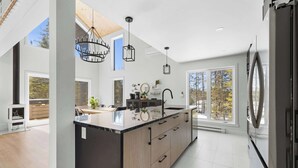 Una cocina moderna con una isla grande, luces colgantes y vistas al exterior.