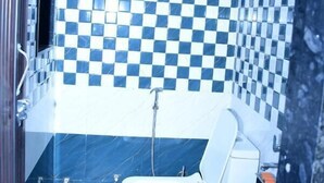 Et badeværelse med et hvidt toilet, en vask og et spejl.