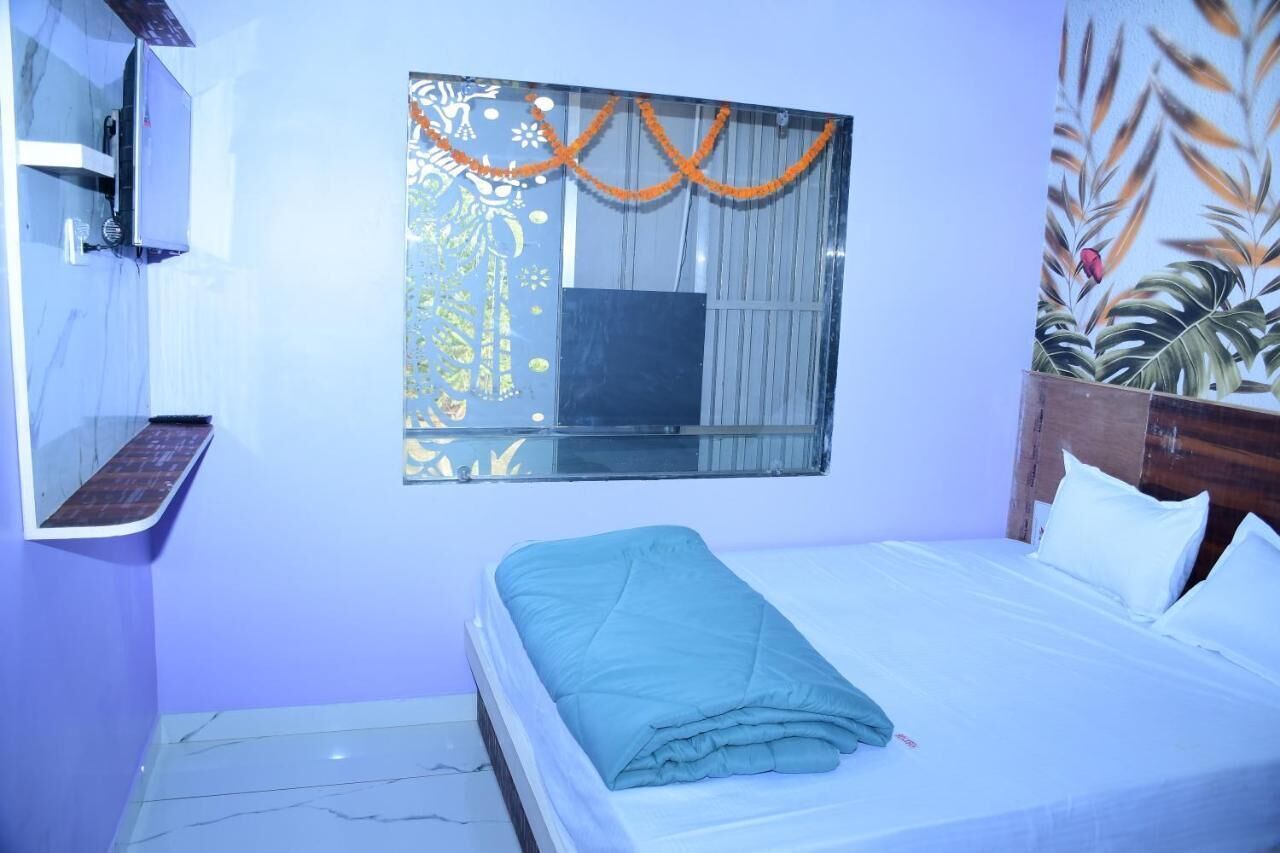 Una camera da letto con un letto, una TV a parete, una finestra con tende e una pianta decorativa.
