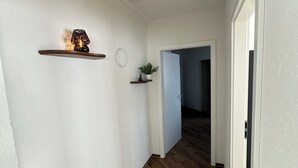 A hallway with white walls, wooden flooring, and a door leading to another room. - In & Out Boardinghouse Deluxe room (Stolberg)