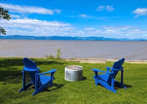 Two blue Adirondack chairs facing a body of water with mountains in the background. - Chalet / Studio #1 Waterfront with Spa, Fireplace & Wifi (Cap-Saint-Ignace)