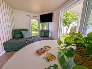 A modern room with a sofa, a table with a board game, and a TV mounted on the wall. - Chalet #2 Waterfront with Spa, Fireplace, Wifi & AC (Cap-Saint-Ignace)