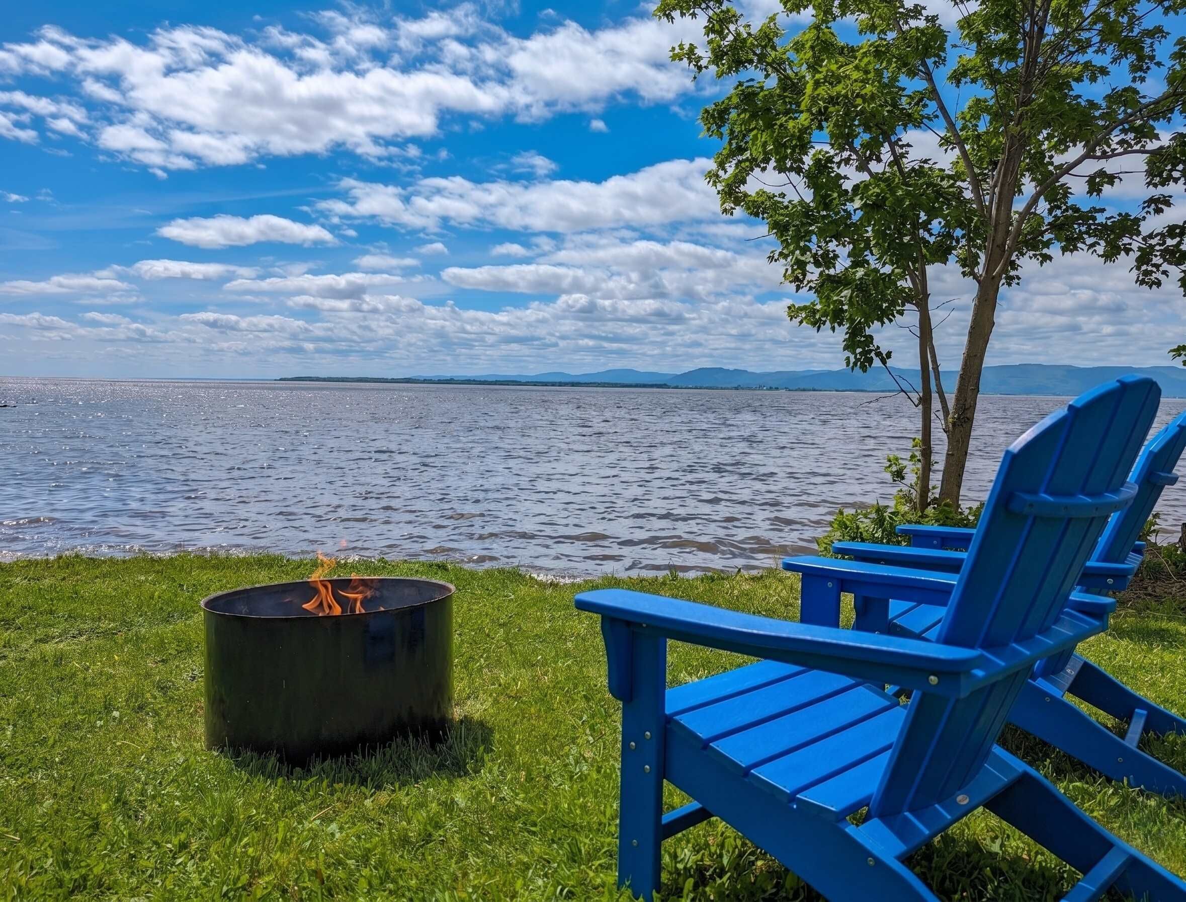 Une vue sur le lac, avec un foyer et des chaises bleues.