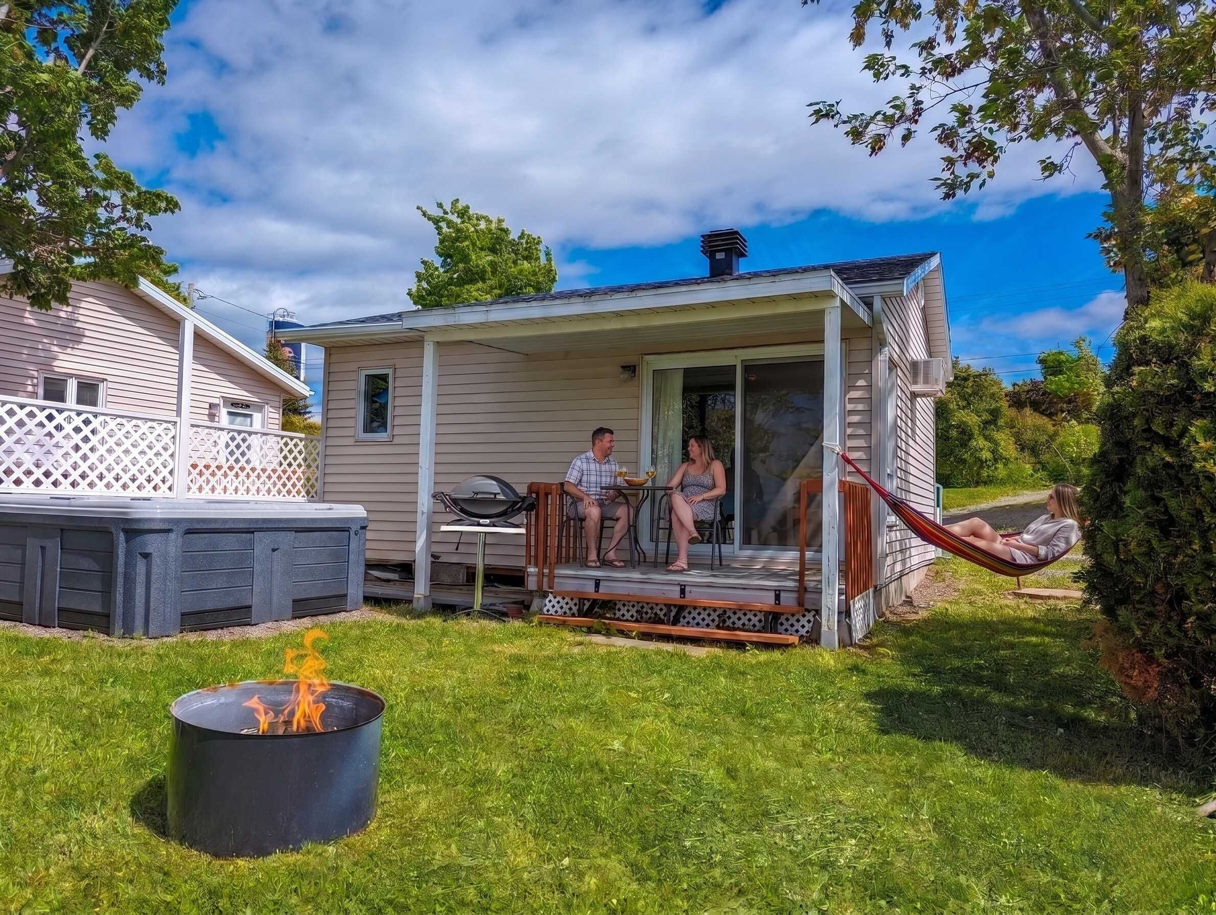 A small house with a porch, a hot tub, and a fire pit.