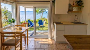 A compact kitchen with a view of the lake, a dining area with a table and chairs, and a small seating area with blue chairs.