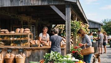 A rustic outdoor market with bread and fresh produce displayed.