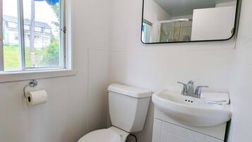 A small, clean bathroom with a toilet, sink, and mirror.