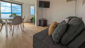 Un salon moderne comprenant un canapé, un téléviseur et un coin repas avec une table et des chaises.
