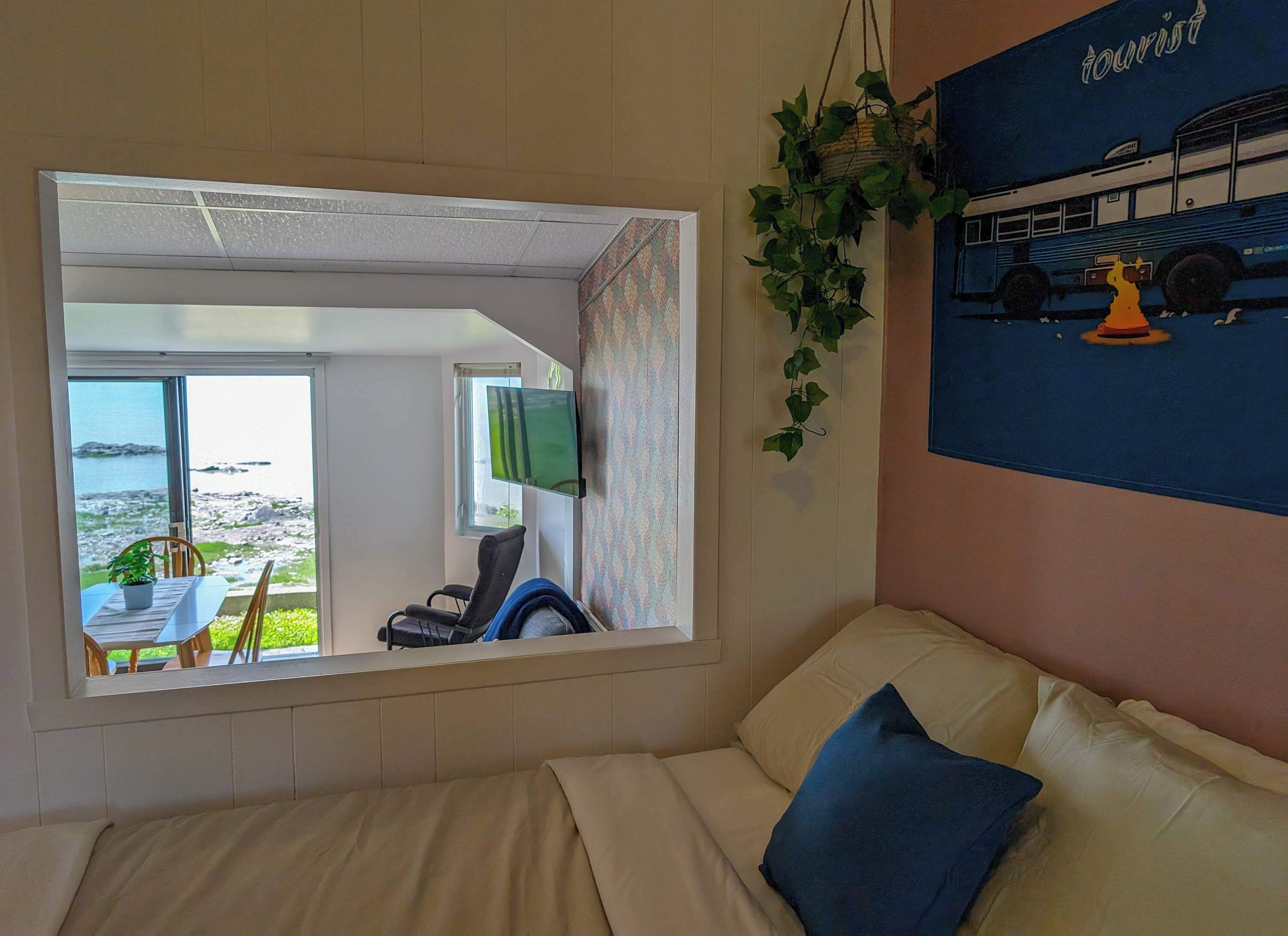 Una habitació amb llit, sofà, televisió i vistes al mar.