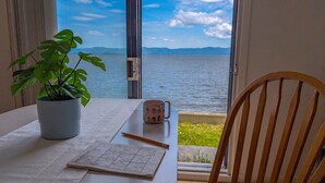 A table with a plant, a mug, and a game board by a window with a view of the sea. - Chalet Studio #6 Waterfront with Spa, Fireplace & Wifi (Cap-Saint-Ignace)