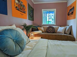 A bedroom with a bed, a sofa, a window with blinds, and wall art. - Chalet Studio #6 Waterfront with Spa, Fireplace & Wifi (Cap-Saint-Ignace)
