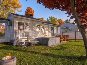 A single-story house with a covered patio, a fire pit, and a lawn. - Chalet #7 Waterfront with Spa, Fireplace, Wifi & AC (Cap-Saint-Ignace)