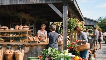 A rustic outdoor market with bread and fresh produce displayed.