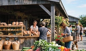Un étal de marché en plein air, rustique, où l’on vend du pain et des légumes.