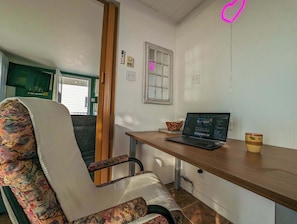 A room with a wooden desk, a laptop, a patterned chair, a window, and a door. - Chalet #9 Waterfront with Spa, Fireplace, Wifi & AC (Cap-Saint-Ignace)