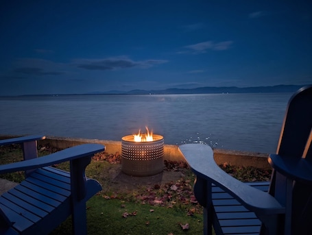 A fire pit with a view of a calm body of water and distant mountains.. Chalet #9 Waterfront with Spa, Fireplace, Wifi & AC