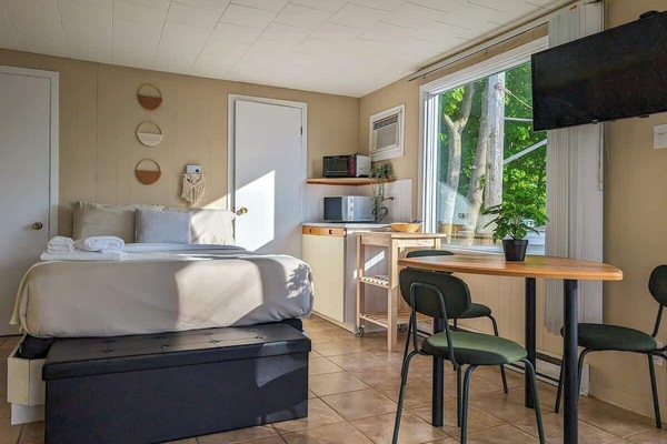 Chalet lumineux et accueillant à aire ouverte, doté d'un lit douillet, d'une kitchenette bien équipée et d'un coin repas baigné de lumiÚre naturelle, l'endroit idéal pour un séjour relaxant.