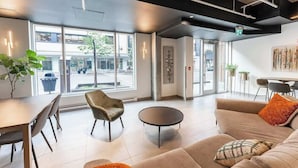 A modern interior with a sofa, chairs, a dining table, and large windows offering a view of the street. - The 708 | For 4 People | Free Parking | BBQ (Québec)