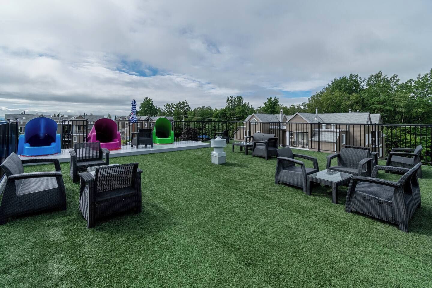 A rooftop patio with outdoor furniture, a slide, and a flag.