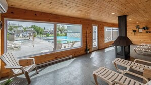 Ein Holzinterieur mit großen Fenstern mit Blick auf einen Pool und Sitzmöglichkeiten im Freien.