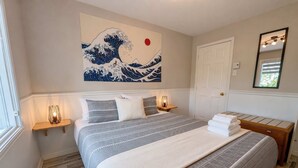 A bedroom with a bed, bedside tables, a wall-mounted artwork, a door, and a mirror. - Riverside Condo w/ Private Hot Tub & Mountain (Sainte-Anne-de-Beaupré)