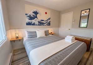 A bedroom with a bed, bedside tables, a wall-mounted artwork, a door, and a mirror. - Condo 1 - Waterfront with SPA, Fireplace & Barbecue (Sainte-Anne-de-Beaupré)
