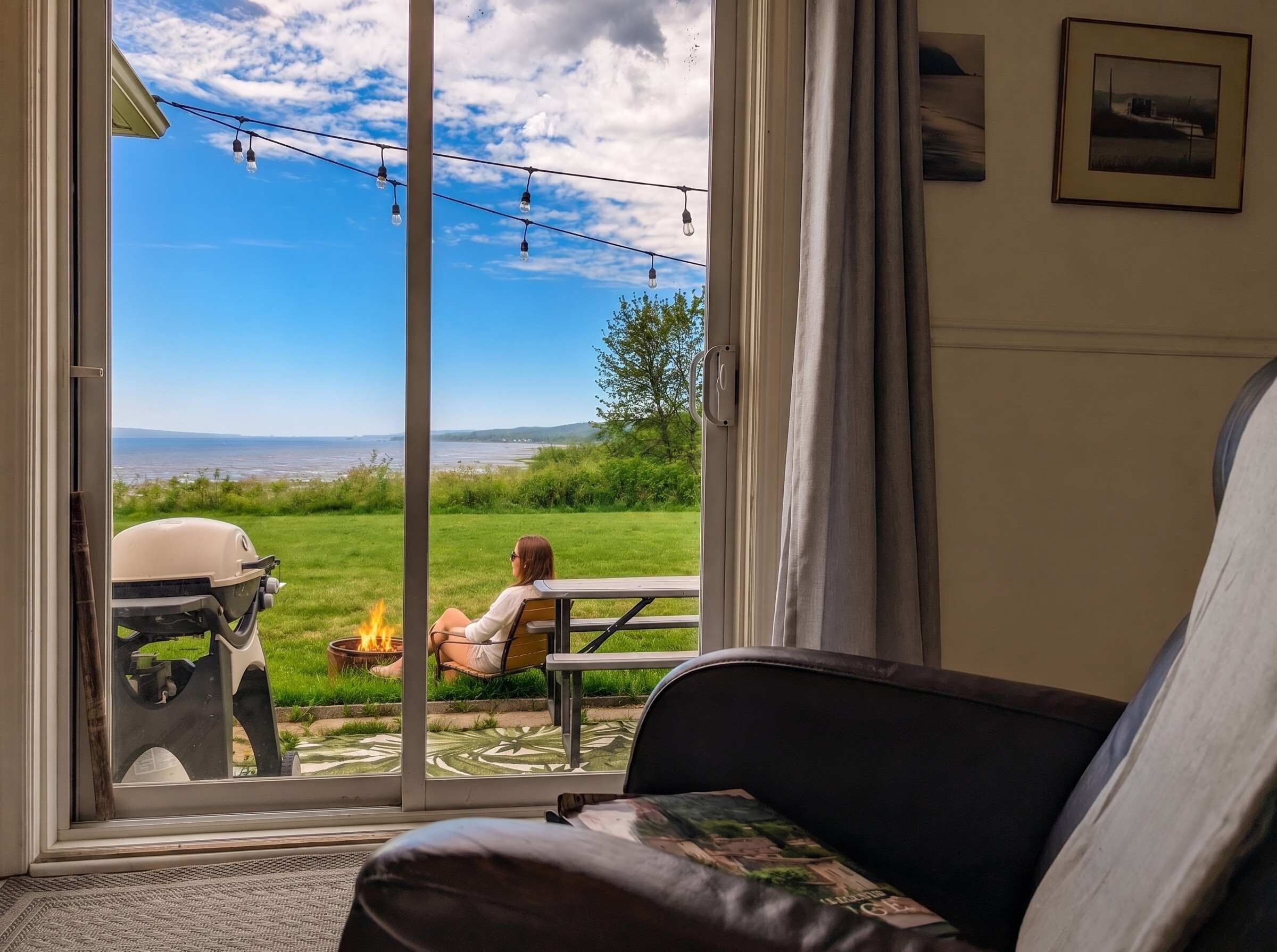 A room with a sliding glass door leading to an outdoor patio with a barbecue grill and a fire pit.