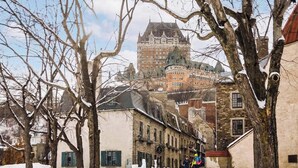 A historic building with a prominent tower, surrounded by trees and other buildings.
