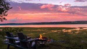 A lakeside view with chairs and a fire pit.