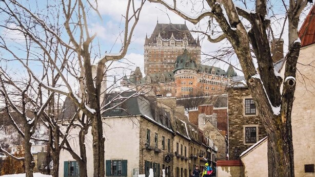 A historic building with a prominent tower, surrounded by trees and other buildings.