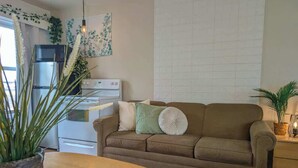 Ein gemütliches Wohnzimmer mit einem braunen Sofa, einem Holztisch und einem Topf mit einer Pflanze.