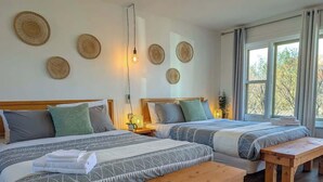 Habitación de hotel con dos camas, un banco de madera y una mesita de noche.