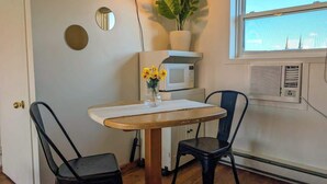 Una cocina pequeña con microondas, una planta en maceta y una ventana con vistas a la ciudad.