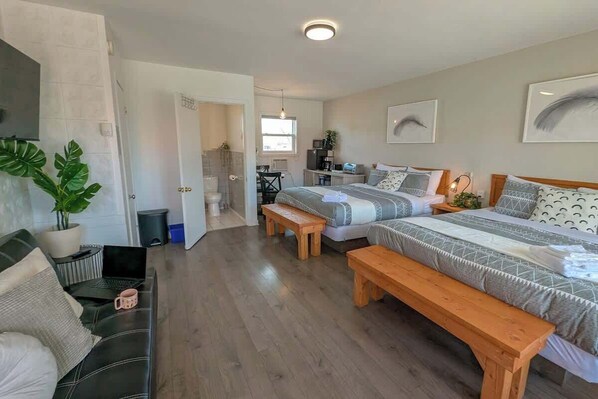 Une chambre moderne avec deux lits, un canapé, un bureau et un espace douche.
