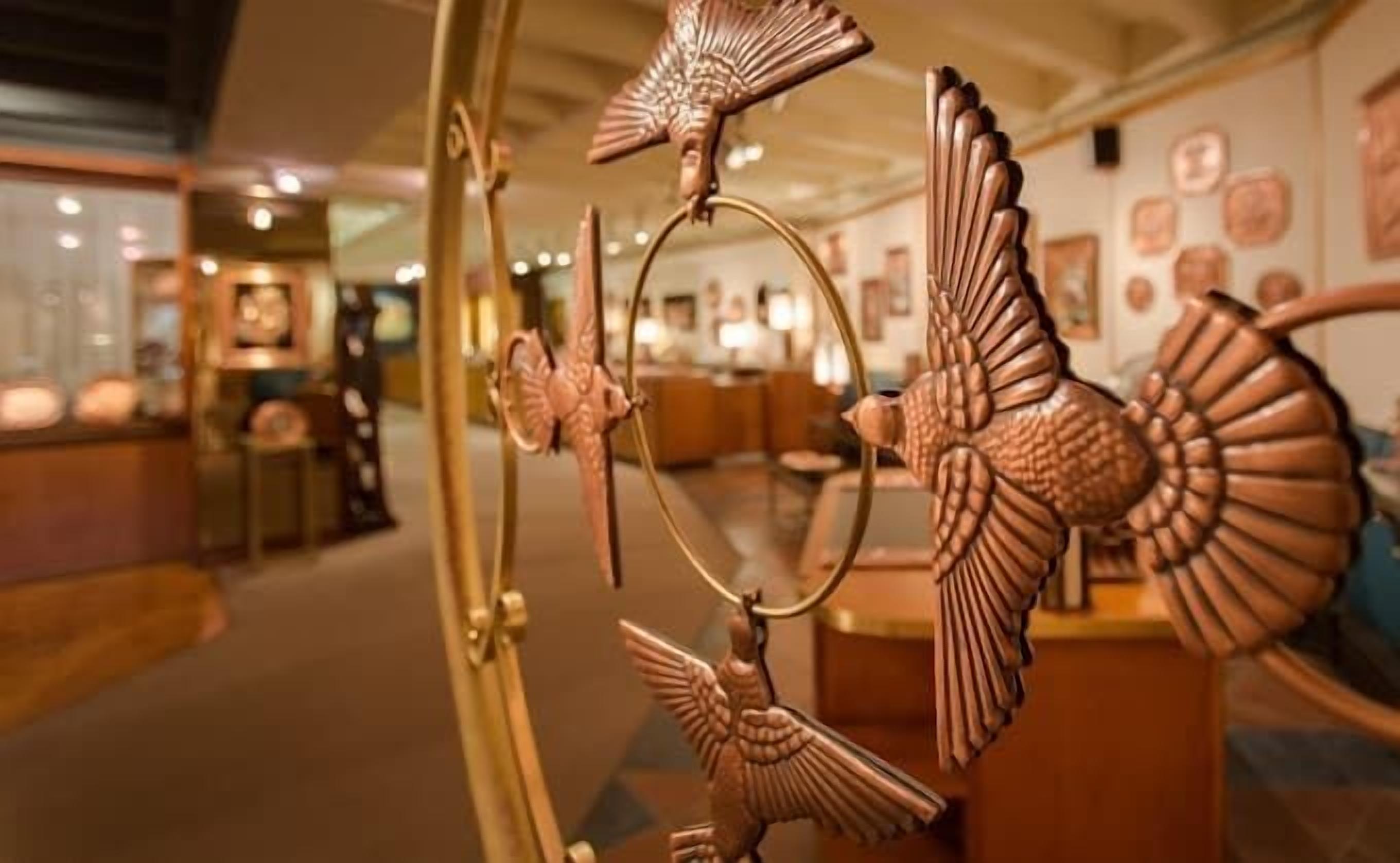 A room with a large mirror reflecting a decorative metal sculpture.