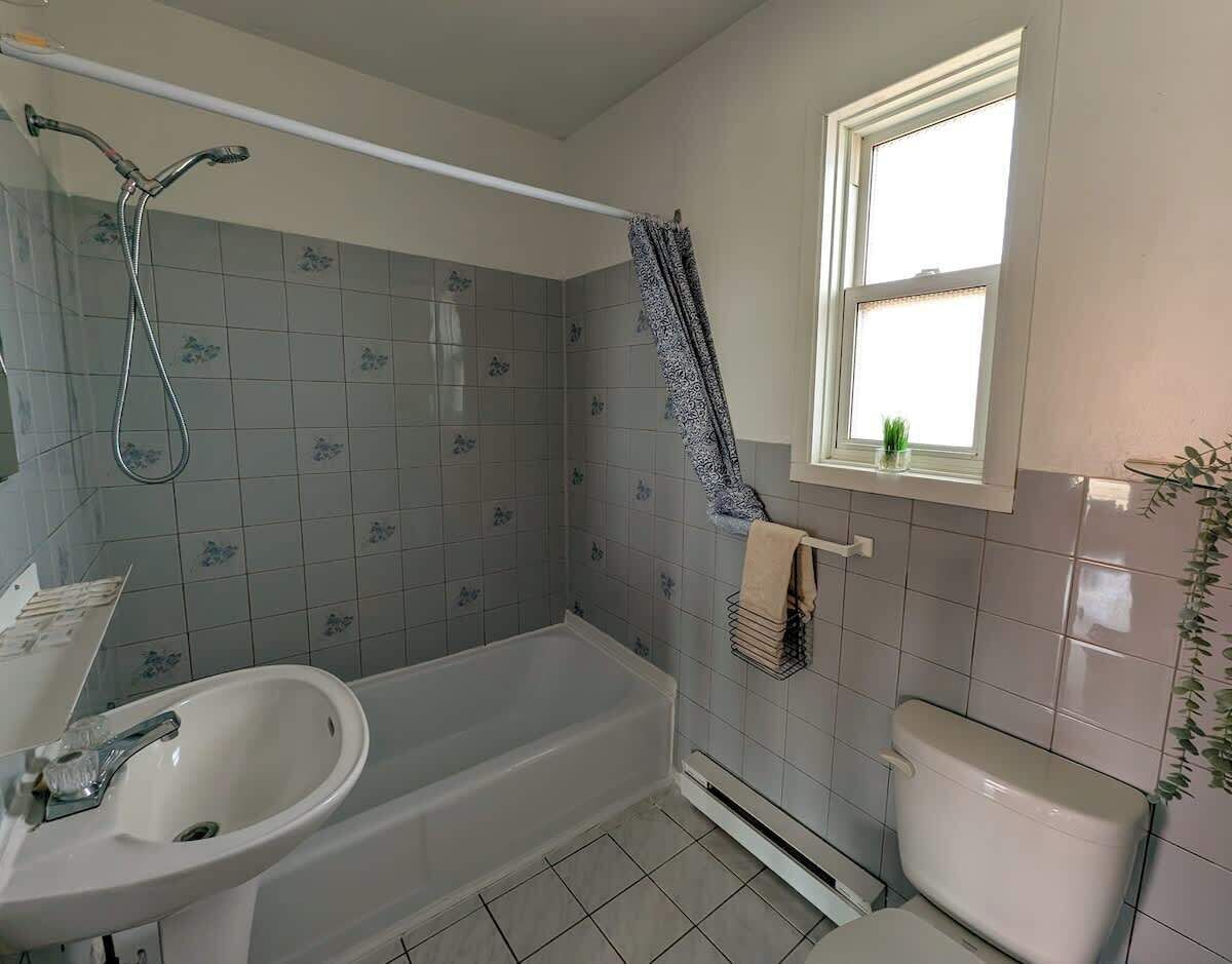 A bathroom with a bathtub, sink, toilet, and a window.