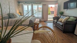 Una sala acogedora con sofá, sillón, cama y televisor.
