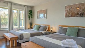 Habitación de hotel con dos camas, bancos de madera y obras de arte en las paredes.