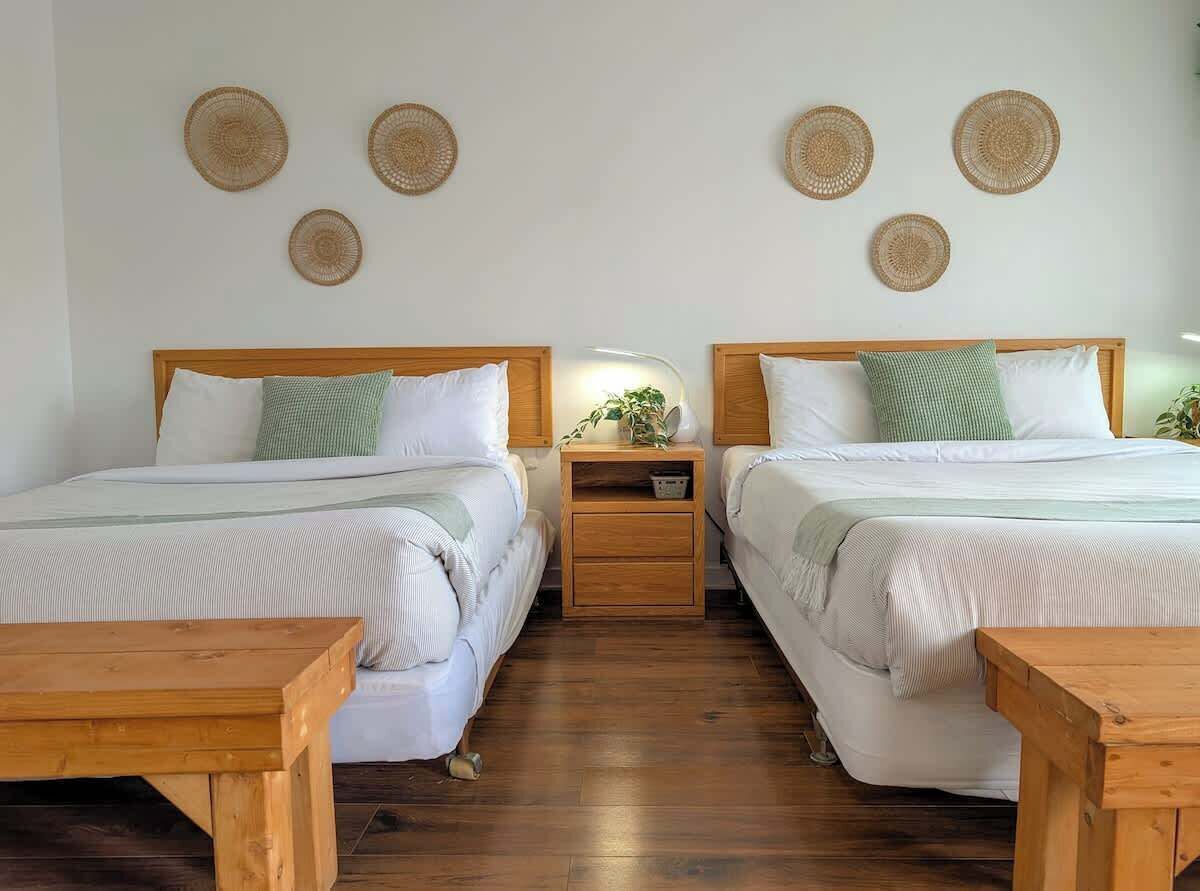 A room with two beds, wooden nightstands, and a small table.