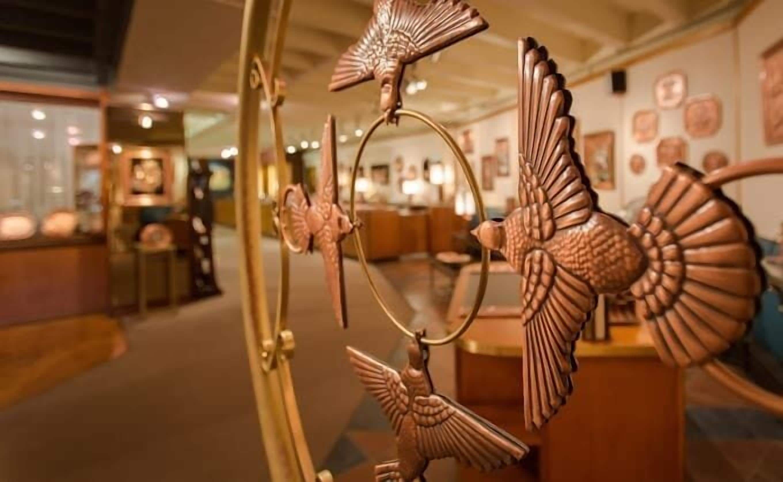 A room with a large mirror reflecting a decorative metal sculpture.