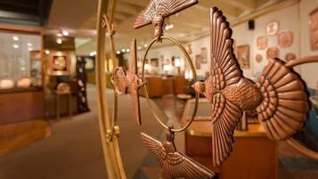 A room with a large mirror reflecting a decorative metal sculpture.