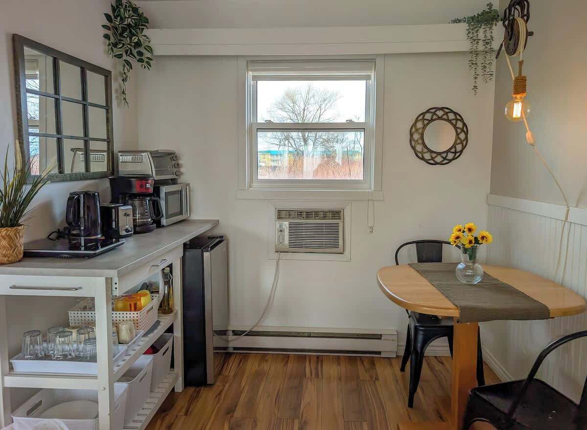 A compact kitchen with a dining area, a window, and a small refrigerator.