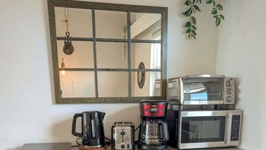 A compact kitchenette with a coffee maker, toaster, microwave, and a laptop on the counter.