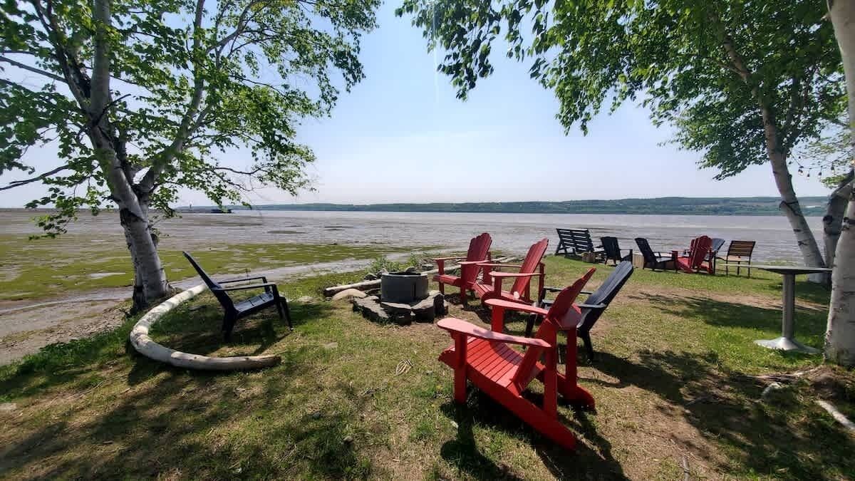 Un espace aménagé au bord du lac, avec des fauteuils Adirondack et un foyer.
