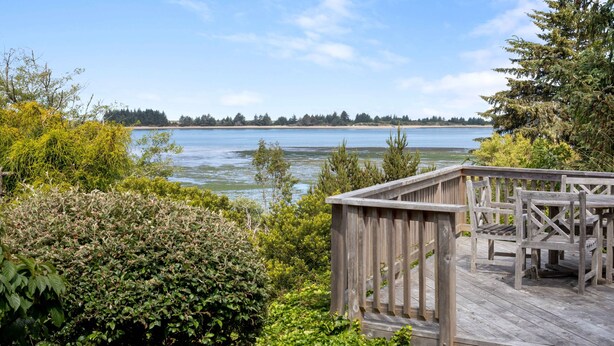 A wooden deck with a bench overlooking a calm lake, surrounded by dense greenery. - Sunset Point - Coos Bay, OR (Coos Bay)
