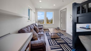 A modern living room with a brown leather sofa, a wooden coffee table, and a black bed frame. - Sunset Point - Coos Bay, OR (Coos Bay)