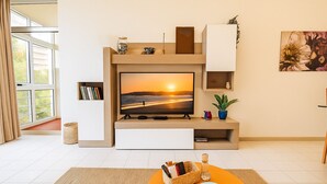 Ein modernes Wohnzimmer mit einem Flachbildfernseher, einer Holz-Unterhaltungsecke, einer kleinen Pflanze und einem Korbwäschetablett.