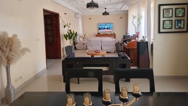 A spacious living room with a modern chandelier, a television, and a comfortable seating area. - Chambres doubles confort (Dakar)