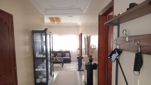 A hallway with a sofa, a glass cabinet, and a black table. - Chambres doubles confort (Dakar)