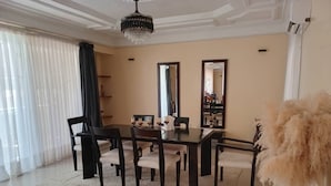 A dining area with a black table, six chairs, and a chandelier. - Chambres doubles confort (Dakar)